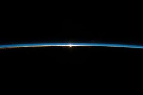 Sun peeking through thin line of Earth’s atmosphere